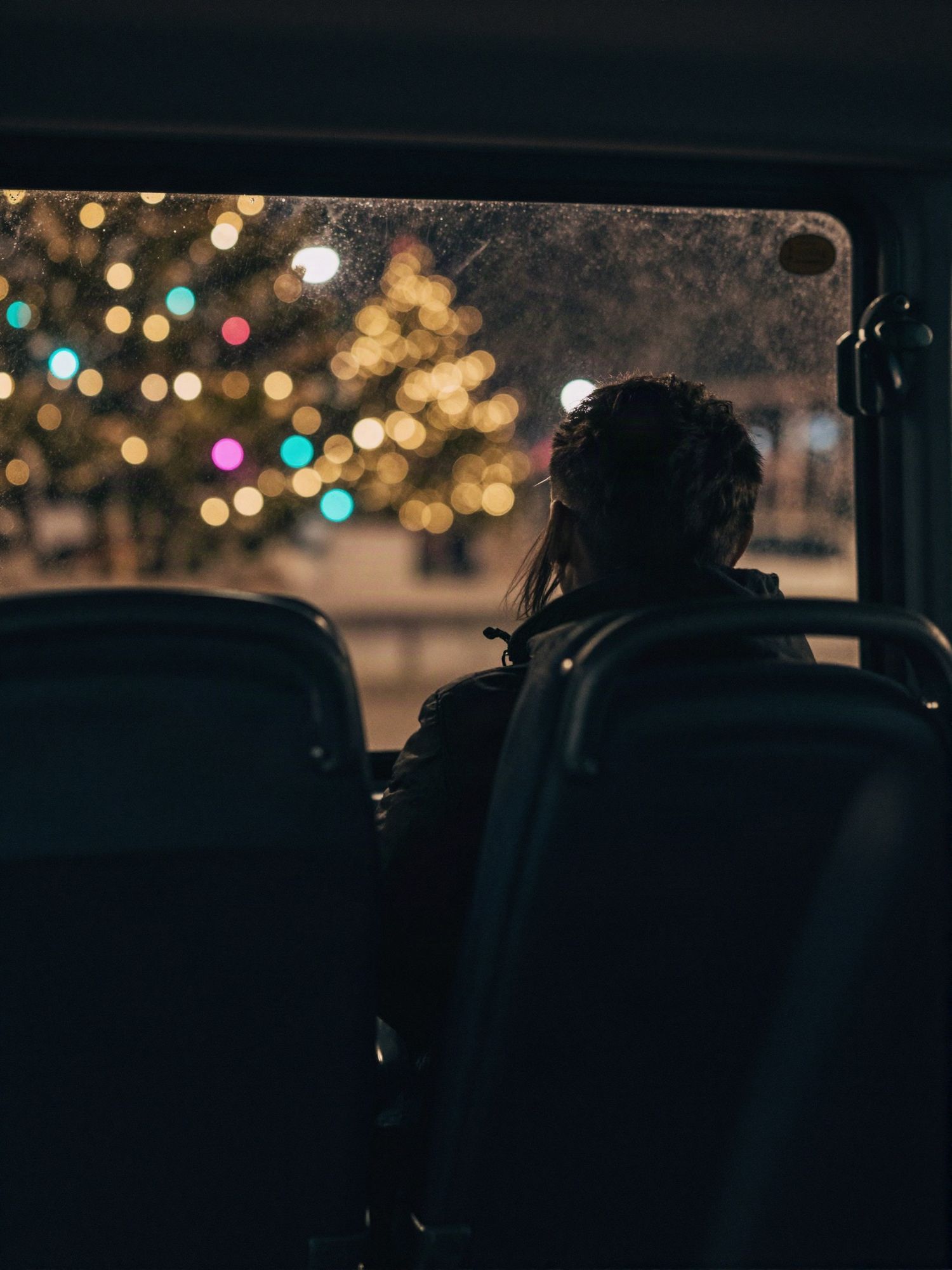 Passageiro olhando luzes de Natal pela janela do ônibus